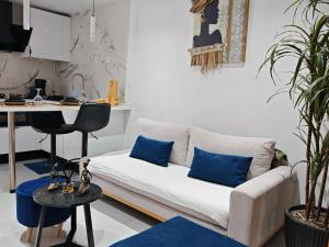 a living room with a white couch and blue pillows at Le Jasmin Appartement in Dar el Haj Ahmed Souid