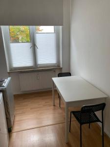 a white table and two chairs in a room with two windows at Gemütliches Apartment in Osnabrück in Osnabrück