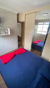 Kleines Zimmer mit einem blauen Bett und einem Spiegel in der Unterkunft Apartamento completo próximo ao aeroporto CNF cidade do galo e cidade adm in Vespasiano