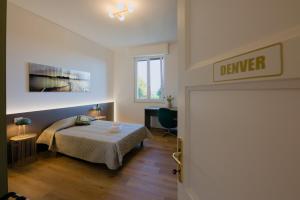 a bedroom with a bed and a desk and a window at Camera Denver - La Casa di Carta Affittacamere in Udine +1 photo