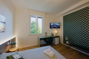 a bedroom with a bed and a desk and a television at Camera Denver - La Casa di Carta Affittacamere in Udine