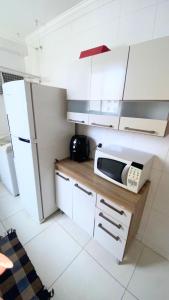eine Küche mit einem weißen Kühlschrank und einer Mikrowelle in der Unterkunft Apartamento completo próximo ao aeroporto CNF cidade do galo e cidade adm in Vespasiano