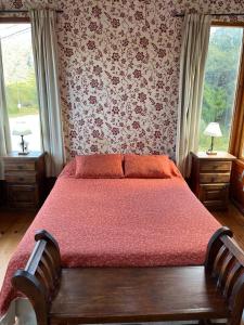 a bedroom with a bed with red sheets and floral wallpaper at Cabañas Ayres del Lago in Potrero de los Funes +36 photos