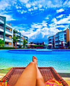a person laying on a bench next to a swimming pool at TerraMaris - Pé na Areia, vista mar, Wifi , Familias, piscinas in Aquiraz
