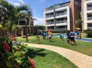 a group of people playing in the grass near a building at TerraMaris - Pé na Areia, vista mar, Wifi , Familias, piscinas in Aquiraz