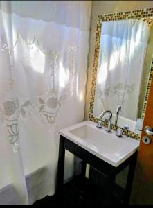 a bathroom with a sink and a shower curtain at Cabañas Ayres del Lago in Potrero de los Funes