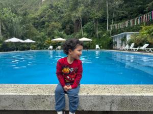 a young boy sitting on a wall by a swimming pool at Donce Extremo in San Carlos +28 photos