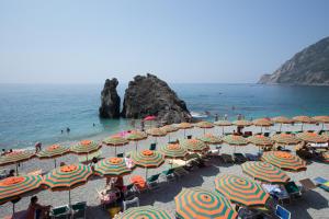 a beach with umbrellas and people on the water at Roca Du Ma Pasu in Monterosso al Mare