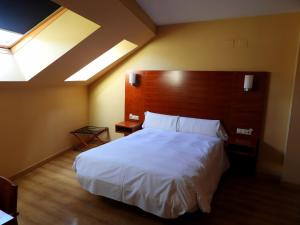 a bedroom with a large white bed with a wooden headboard at Hotel Ruta de la Plata de Asturias in Pola de Lena