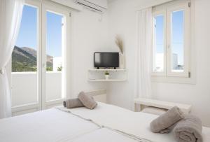 a white bedroom with a bed and a tv at Sunny Villa Sifnos in Apollonia +42 photos