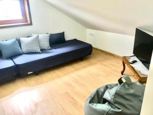 a living room with a blue couch and a television at Azurara Martins House in Azurara