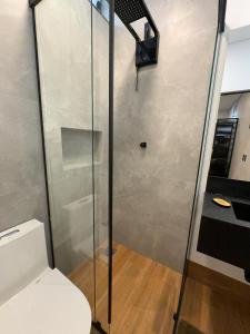 a bathroom with a toilet and a glass shower at 2Kitnet aconchegante no coração da cidade in Lavras