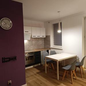 a kitchen with a table and chairs and a clock at Apartament Jana in Warsaw