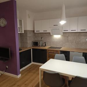 a kitchen with white cabinets and a table with chairs at Apartament Jana in Warsaw +21 photos
