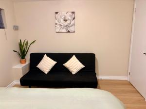 a black couch with two pillows in a room at Vita House near Downsview and Yorkdale Shopping Center in Toronto