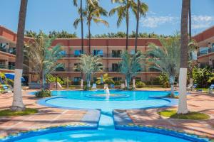 a pool with palm trees in front of a building at Nk Hotel Nekié Tepic in Tepic