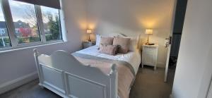a bedroom with a white bed and two windows at The Willows in Stockton-on-Tees