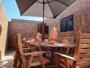 a wooden table with chairs and an umbrella at Maison almassira in Agadir