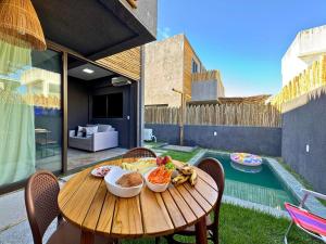 einen Holztisch mit Schalen aus Essen auf einer Terrasse in der Unterkunft MHV Milagres - Studio Guadalupe 05, quarto e sala privativo a poucos metros da Praia do Marceneiro in Passo de Camarajibe