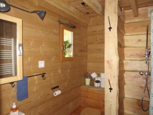 a wooden bathroom with a shower in a log cabin at La Cabane aux Sapins in Ratières