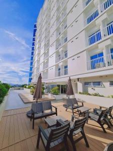 Cozy Studio Unit - Inspiria Condominium Beside Abreeza Mall في مدينة دافاو: فناء فيه كراسي ومظلات ومبنى