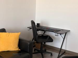 una scrivania nera con una sedia accanto a un divano di BrasoVista - PAJ Premium Apartments in URBAN Plaza a Braşov
