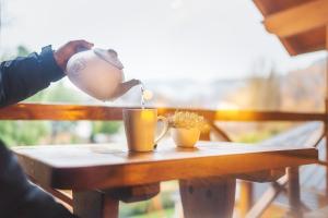 eine Person, die Kaffee in eine Tasse auf einem Tisch gießt in der Unterkunft Cabañas centricas Rotui Patagonia Group in San Martín de los Andes