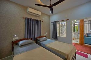 a bedroom with two beds and a ceiling fan at The Panakal Boho in Cochin