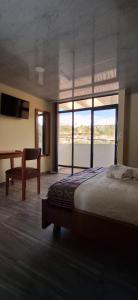 a bedroom with a bed and a desk and a window at Hotel San Marcos Las Lajas in Ipiales