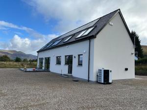 a white building with solar panels on top of it at Eco-Friendly Highland Suite with Mountain Views in Spean Bridge