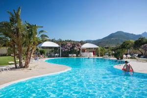 a woman holding a surfboard in a swimming pool at Hotel San Teodoro in San Teodoro
