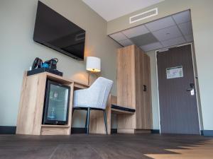 a chair sitting in a room with a tv at Heeren van Noortwyck in Noordwijk aan Zee