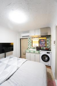 a bedroom with a white bed and a kitchen at 御嶽ハウス in Tokyo