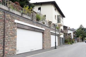 two white garage doors on a brick building at Gran Hogar Chic I 8 min de los remontes con balcón in La Massana
