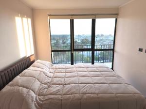 a large bed in a room with a large window at Departamento amoblado in San Pedro de la Paz