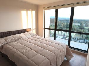 a bedroom with a large bed and large windows at Departamento amoblado in San Pedro de la Paz