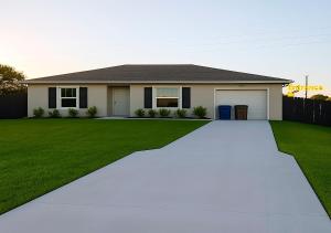 a house with a driveway in front of a yard at Cozy with Private Entry Near Fort Myers & Airport in Lehigh Acres