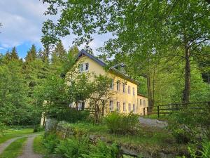a yellow house in the middle of a forest at gemütliche Ferienwohnung Schwarzmühle in Börnichen