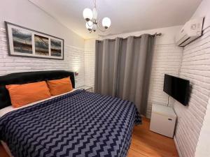 a bedroom with a bed and a flat screen tv at F&F alojamiento in Punta del Este