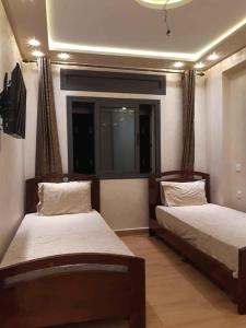 a bedroom with two beds and a window at Résidence al BASSLAM agadir in Agadir