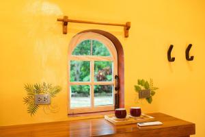 a yellow room with a window and a wooden table at La Maison - Siquijor in Siquijor