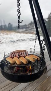 een grill met hotdogs en kampvuurtjes erop bij Modern and cozy mountain cabin - panoramic view! in Torvetjørn