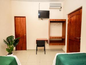 a room with two beds and a desk and a tv at Tariri Hotel in Pucallpa