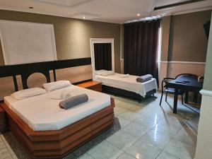 a hotel room with two beds and a table at Hotel Vitória de Santos in Santos