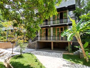 Una casa con balcón y árboles delante. en Mindara Villa, en Galle