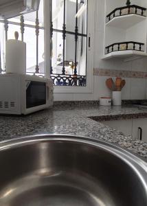 a stainless steel sink in a kitchen with a microwave at Casa Paco & Carmela in Algodonales +34 photos
