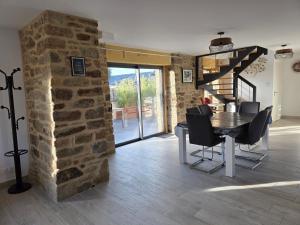 ein Esszimmer mit einem Tisch und einer Steinwand in der Unterkunft les hirondelles in Péaule