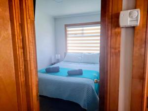 a bedroom with a bed with blue sheets and a window at Cabañas Ruben Dario 1 in Puerto Natales