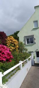 a white fence in front of a building with flowers at chambre d'hôte la maison verte in Séglien