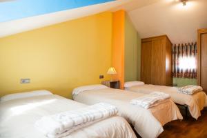 three beds in a room with yellow walls at Asturica in Astorga